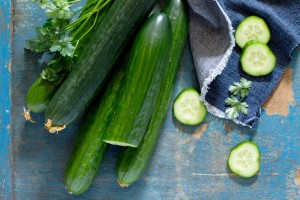 Fresh organic cucumbers on a wooden table, top view. Space for your text.